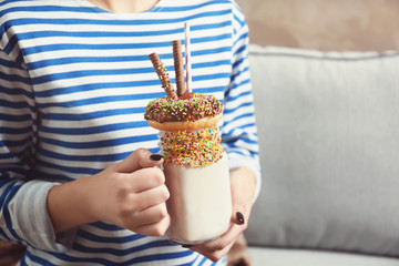 Girl holding milkshake with donut and other sweets in jar