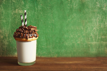 Milkshake, donut and other sweets in glass on green background