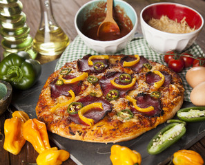 Tasty pizza, tomatoes and others ingredients on a wooden backgro