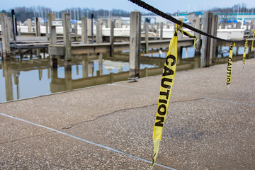 hanging caution tape strips over marina sidewalk