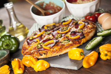 Tasty pizza, tomatoes and others ingredients on a wooden backgro