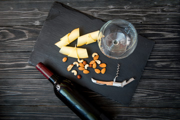 bottle of red wine, appetizers and corkscrew on wooden background