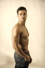 Handsome shirtless muscular man's profile, looking away, on light background in studio shot