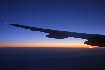 Fototapeta na wymiar dawn light on the cloud under the airplane wing