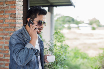 Young man with smartphone smiling relaxing at cafe.