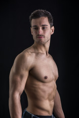 Fototapeta premium Handsome shirtless muscular man's profile, looking away, isolated on black
