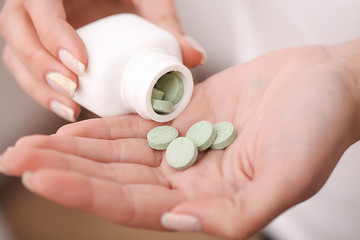 Woman holding pill in hand.