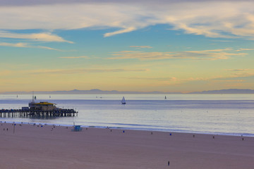 The Pacific Ocean is during sunset. Landscape of beach has pier and boats, the USA, Santa Monica. 