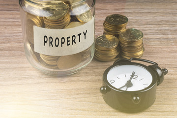 Coins in glass with PROPERTY label on wooden background. Financial concept.