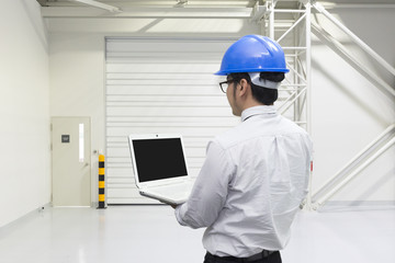 The  engineer hold the laptop by the hand at the inside of the factory