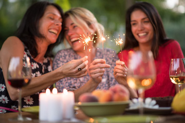 Three beautiful women having fun while they hold spark sticks