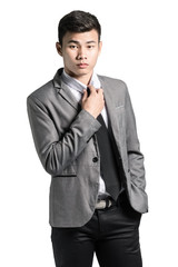 Portrait of a young businessman adjusting his tie. Isolated on w