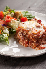 Homemade Italian four cheese lasagna with a side salad close view
