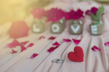 Obraz premium Close up of wedding rings and red heart handmade with love on the bottle for Valentine's day or wedding background