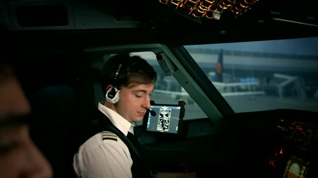 Modern plane or aircraft at the airport runway. The close shot of first pilot's hand. He turns on switches at the overhead control panel of Airbus A319 A320 A321. Shot at training center