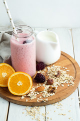 blackberry smoothie in a bottle, nuts, oatmeal, milk jug on a tray closeup