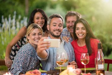 Friends taking a selfie on a terrace by a summer evening