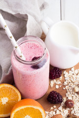 blackberry smoothies in a glass bottle with a straw close-up