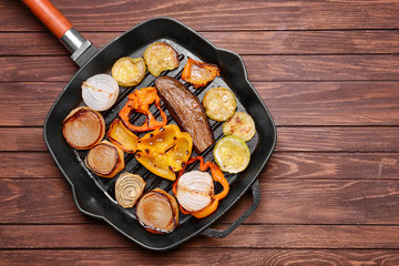Iron cast pan with grilled vegetables on wooden background