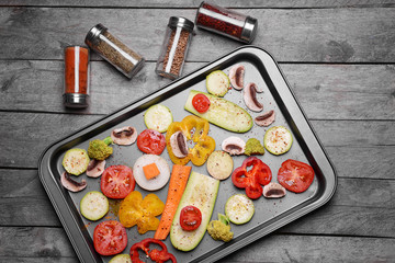 Fototapeta na wymiar Baking tray with raw vegetables on wooden background