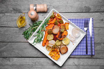 Plate with grilled vegetables on wooden background