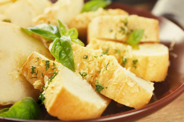 Slices of tasty bread with garlic and herbs on plate, close up