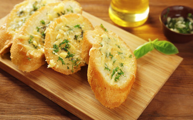 Tasty bread with garlic, cheese and herbs on kitchen table