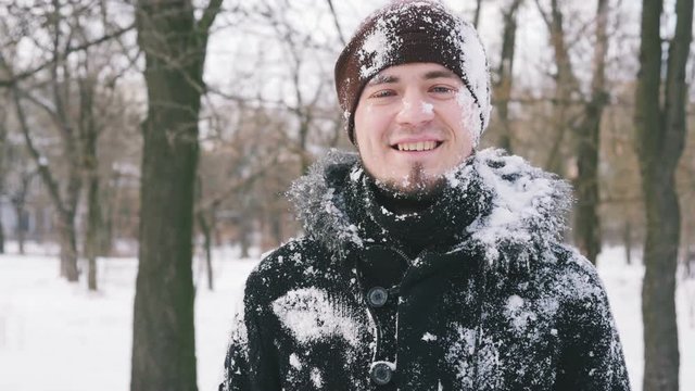 Guy getting snowball on head while playing with his friends, slow motion