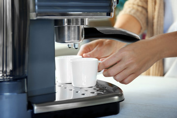 Fototapeta na wymiar Woman making aromatic espresso in coffee machine, closeup