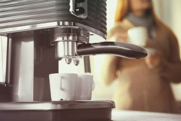 Closeup of making aromatic espresso in coffee machine and woman on background