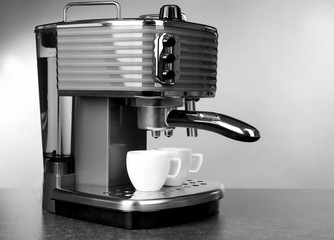 Modern coffee machine with cups on grey table
