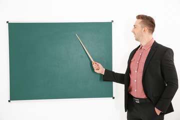 Young male teacher beside blackboard on white blackboard