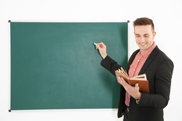 Young male teacher beside blackboard on white blackboard