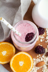 smoothie in a glass bottle with a straw, white milk jug, close-up oranges