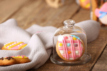 Glass cover with colourful Easter cookies on wooden table