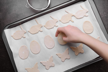Woman putting raw Easter cookies on baking tray, closeup