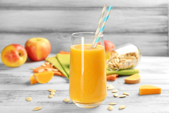 Glass of pumpkin smoothie with apples on table