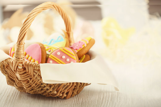 Wicker basket with tasty Easter cookies and napkin, closeup