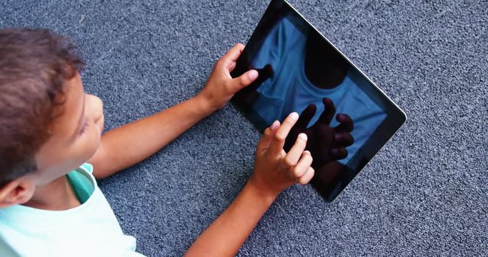 Slow motion of schoolboy lying on floor and using digital tablet in library at school 4k