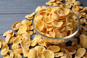 Glass bowl with cornflakes on grey wooden background