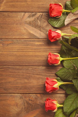 Naklejka na ściany i meble Beautiful red roses on wooden background