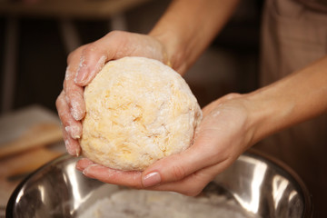 Young woman making dough in kitchen, closeup