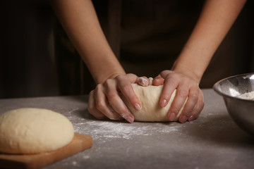 Woman making dough on kitchen table, closeup