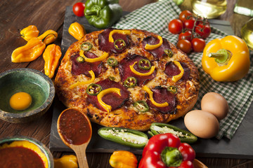Tasty pizza, tomatoes and others ingredients on a wooden backgro