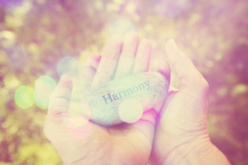 Hands holding stone with the word Harmony.  Instagram effect.