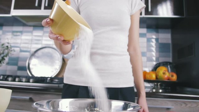 Young woman pouring sugar in bowl, close up, slow motion