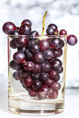Red grape bunch in the clear glass with white bokeh background