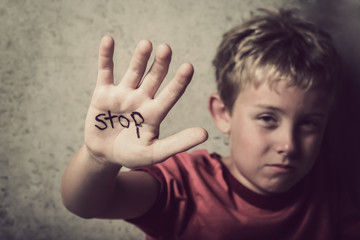 Scared boy with Stop written on his hand