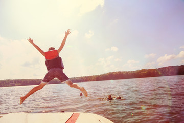 Fototapeta na wymiar Kids jumping off a boat into the lake. Instagram effect.
