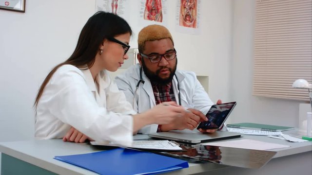 Two doctors discussing X-ray image on tablet